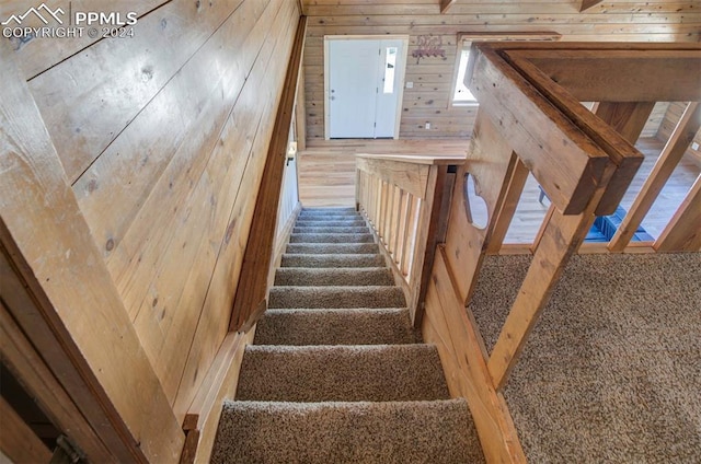 stairway with carpet flooring and wood walls