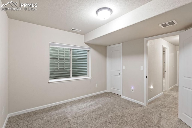 spare room featuring a textured ceiling and carpet flooring