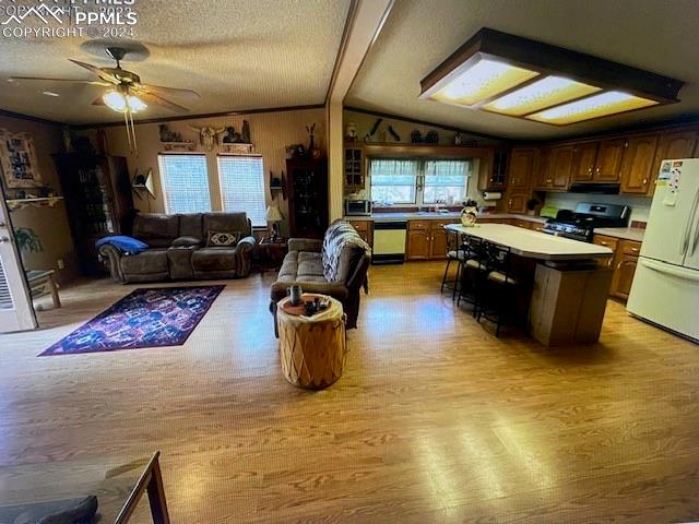 kitchen featuring lofted ceiling with beams, ceiling fan, white appliances, and light hardwood / wood-style floors