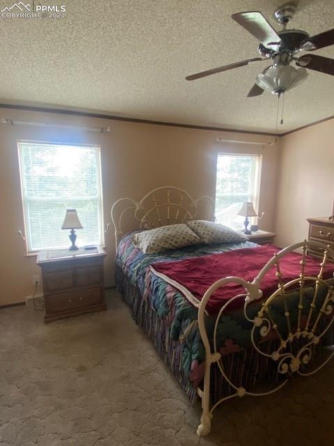 bedroom with a textured ceiling, carpet floors, and ceiling fan