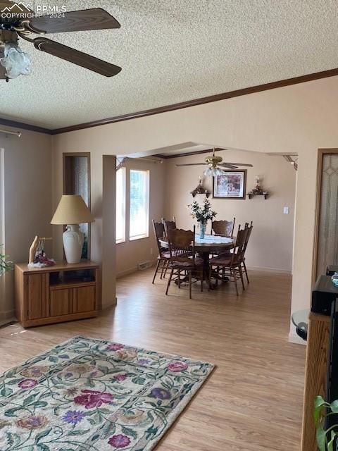 dining room featuring a textured ceiling, crown molding, hardwood / wood-style floors, and ceiling fan