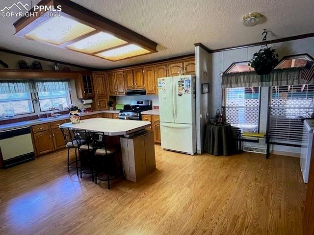 kitchen with light hardwood / wood-style flooring, white appliances, vaulted ceiling, extractor fan, and a center island