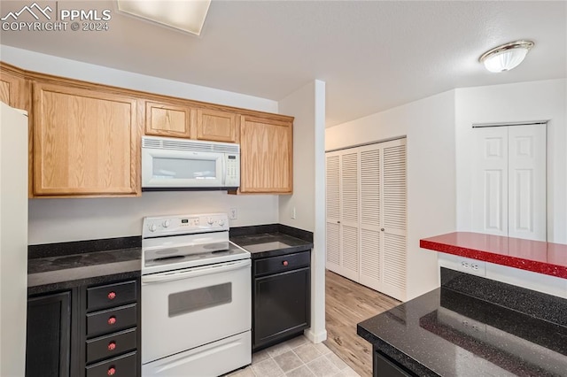 kitchen featuring dark stone countertops and white appliances