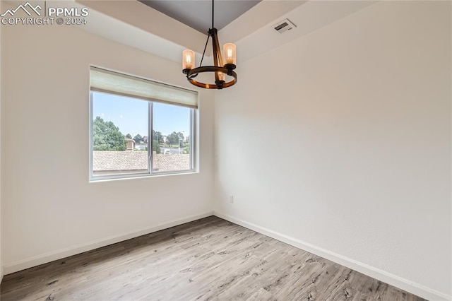 spare room with hardwood / wood-style flooring and a notable chandelier