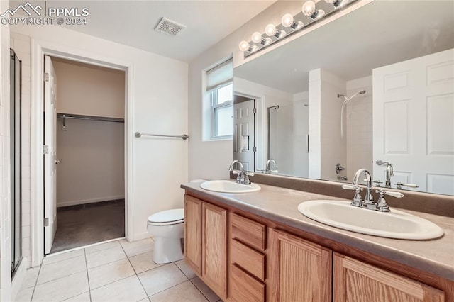 bathroom with tile patterned floors, toilet, vanity, and tiled shower