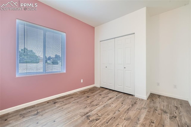 unfurnished bedroom with light hardwood / wood-style flooring and a closet