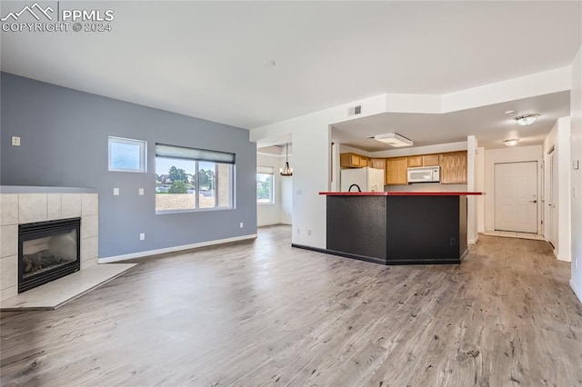 kitchen with a fireplace, light hardwood / wood-style flooring, light brown cabinetry, and white appliances