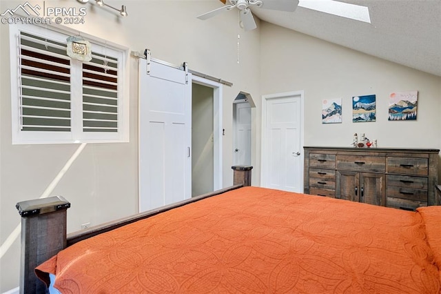 bedroom with a skylight, high vaulted ceiling, a barn door, and ceiling fan