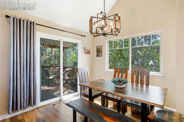 dining room with a notable chandelier, wood-type flooring, and vaulted ceiling