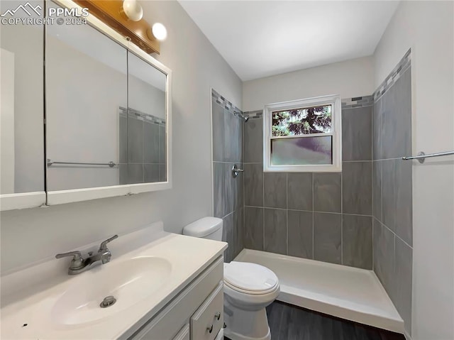 bathroom featuring tiled shower, vanity, and toilet