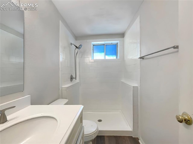 bathroom featuring vanity, toilet, wood-type flooring, and tiled shower