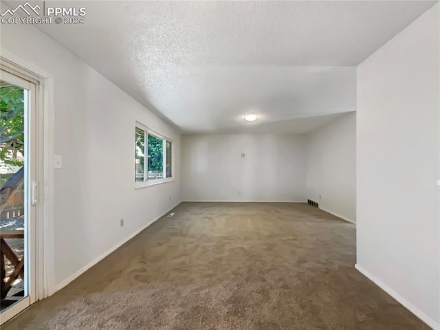 spare room featuring dark colored carpet and a textured ceiling