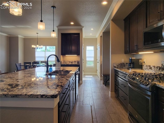 kitchen with sink, decorative light fixtures, dark stone counters, appliances with stainless steel finishes, and a healthy amount of sunlight