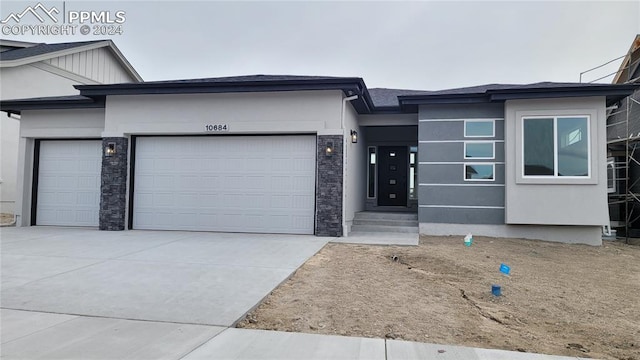 prairie-style house with a garage, concrete driveway, and stucco siding