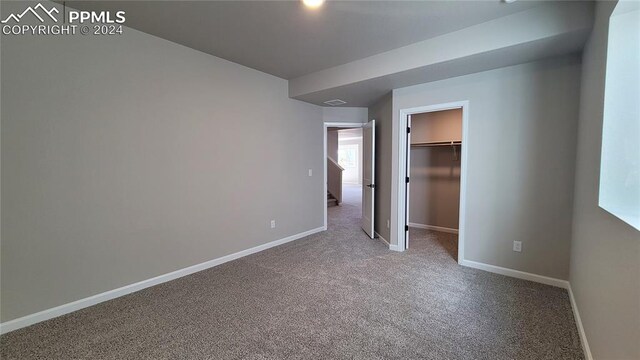 unfurnished bedroom featuring carpet flooring, a spacious closet, and a closet