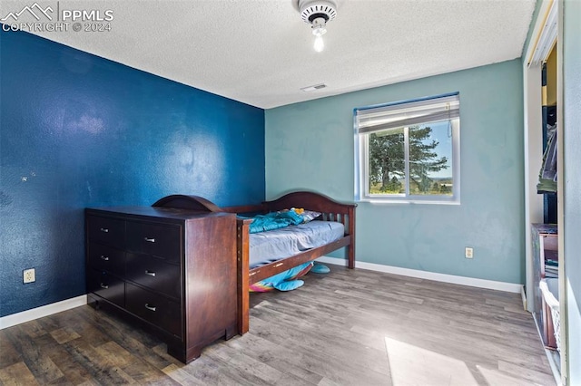 bedroom featuring hardwood / wood-style floors and a textured ceiling