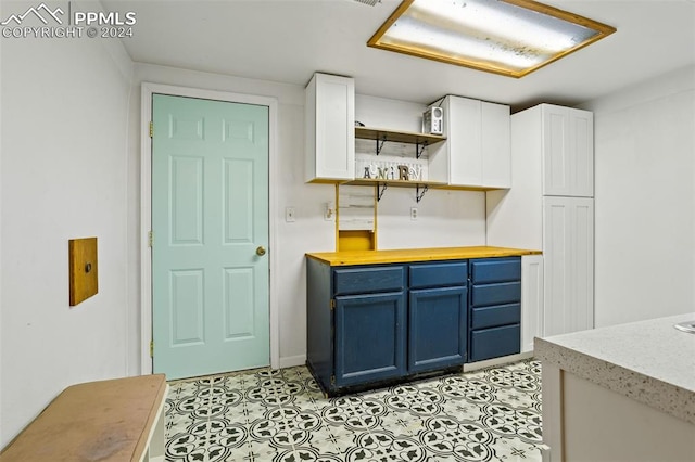 kitchen featuring white cabinetry, blue cabinets, and light tile patterned floors