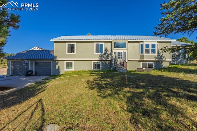 raised ranch featuring a garage and a front lawn