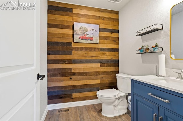 bathroom featuring vanity, toilet, wood-type flooring, and wood walls