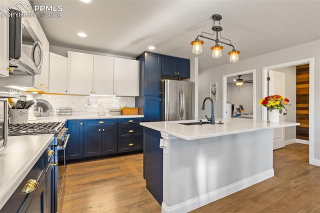 kitchen with blue cabinets, hardwood / wood-style flooring, an island with sink, and appliances with stainless steel finishes