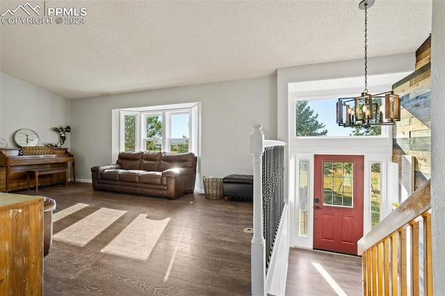 interior space featuring dark wood-type flooring, an inviting chandelier, a textured ceiling, and a wealth of natural light