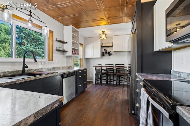 kitchen featuring sink, white cabinetry, appliances with stainless steel finishes, pendant lighting, and decorative backsplash