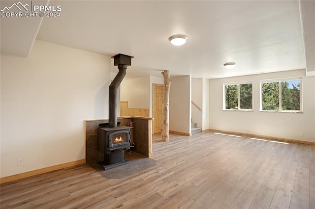 unfurnished living room featuring hardwood / wood-style flooring and a wood stove