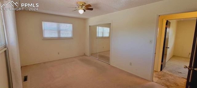 unfurnished bedroom featuring ceiling fan, a textured ceiling, and light colored carpet