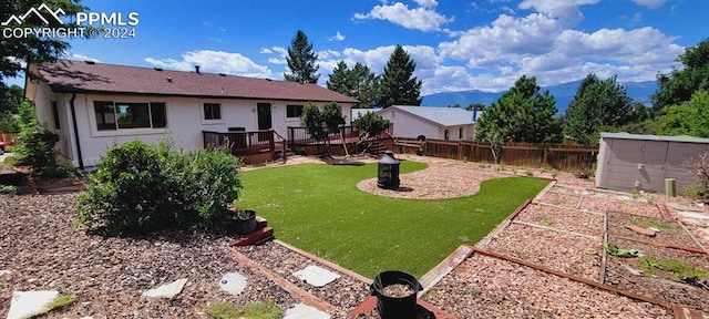 view of yard featuring a deck with mountain view and an outbuilding