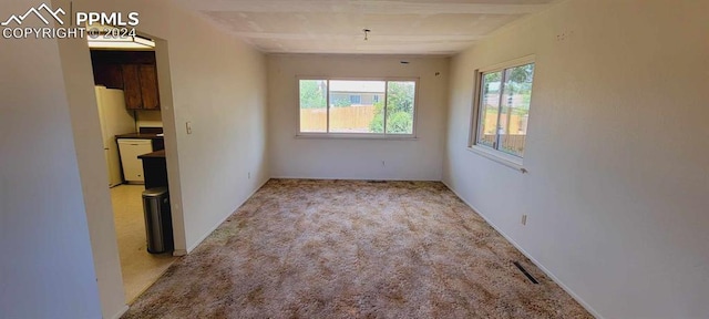 spare room with beam ceiling and light colored carpet