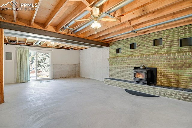 unfurnished living room featuring ceiling fan, a wood stove, and concrete floors