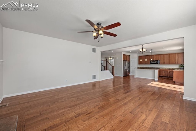 unfurnished living room with ceiling fan with notable chandelier and hardwood / wood-style flooring