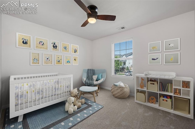 carpeted bedroom with ceiling fan and a crib