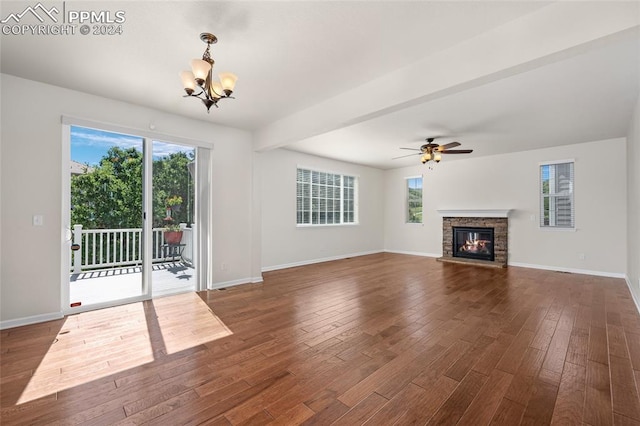 unfurnished living room featuring ceiling fan with notable chandelier, dark hardwood / wood-style floors, and a fireplace