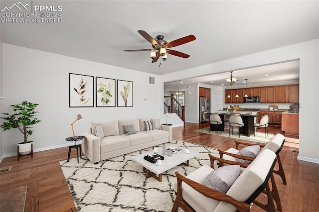 living room with dark hardwood / wood-style flooring and ceiling fan with notable chandelier