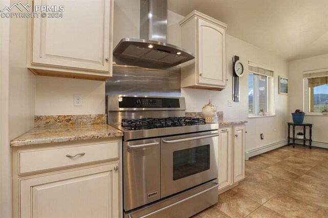 kitchen featuring double oven range, light stone countertops, a baseboard heating unit, and wall chimney range hood