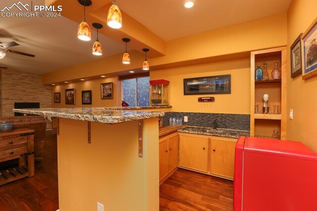 kitchen featuring decorative light fixtures, dark wood-type flooring, a kitchen bar, and kitchen peninsula