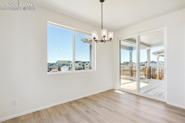 unfurnished dining area featuring an inviting chandelier and light wood-type flooring