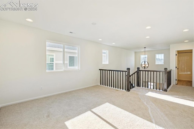 empty room featuring light colored carpet and a chandelier