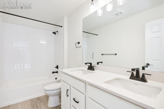 full bathroom with hardwood / wood-style floors, vanity,  shower combination, and toilet