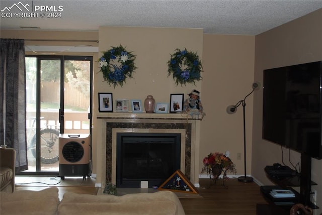 living room with a textured ceiling, a premium fireplace, and hardwood / wood-style floors