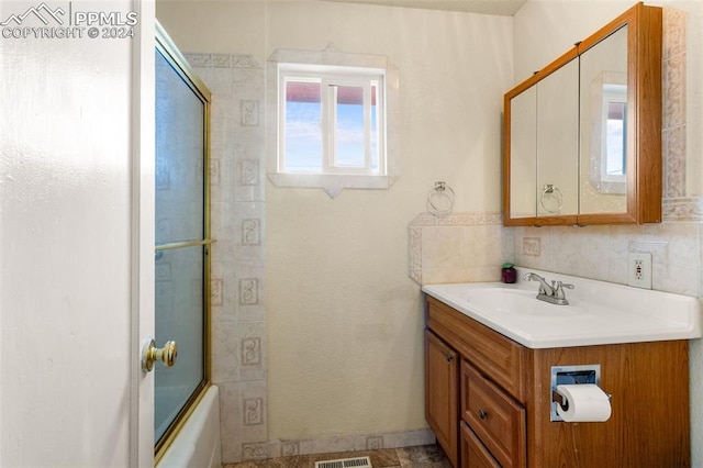 bathroom with vanity and shower / bath combination with glass door