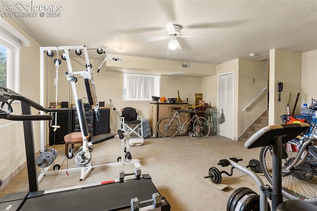 workout room with a textured ceiling, carpet floors, and ceiling fan