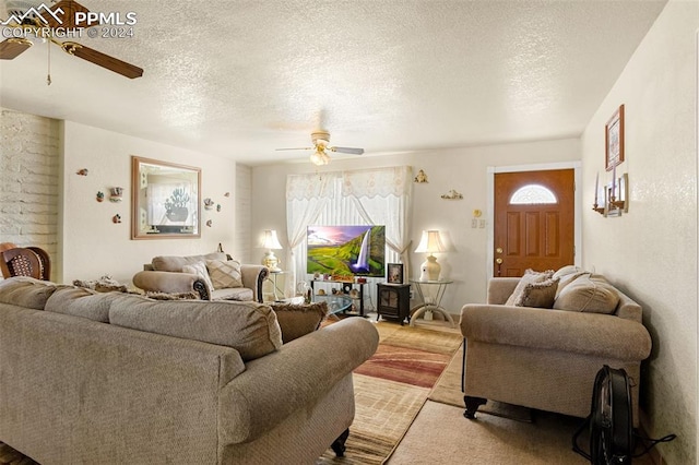 living room featuring ceiling fan and a textured ceiling