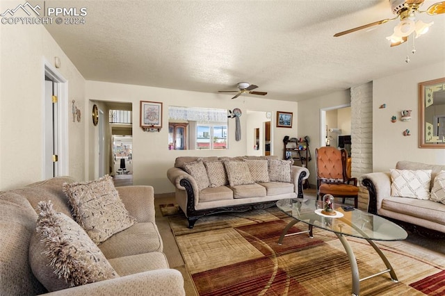 living room with ceiling fan and a textured ceiling