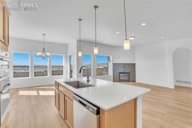 kitchen with appliances with stainless steel finishes, a sink, light wood-type flooring, recessed lighting, and a kitchen island with sink