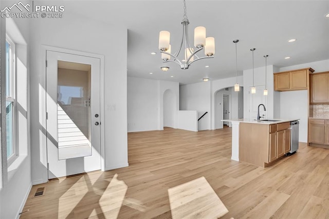 kitchen featuring a sink, arched walkways, recessed lighting, open floor plan, and dishwasher