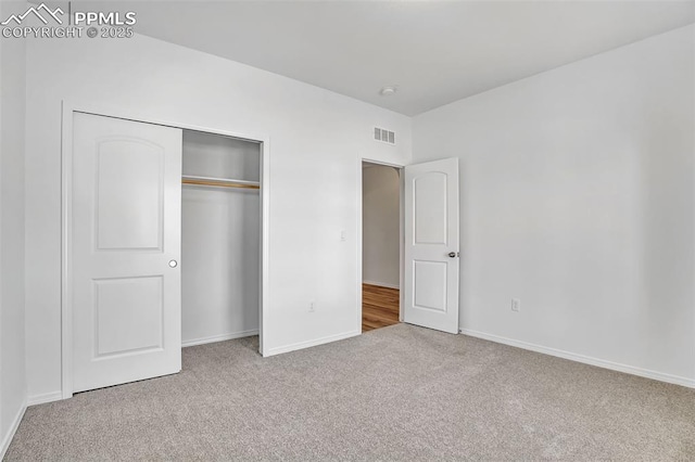 unfurnished bedroom with carpet floors, baseboards, and a closet