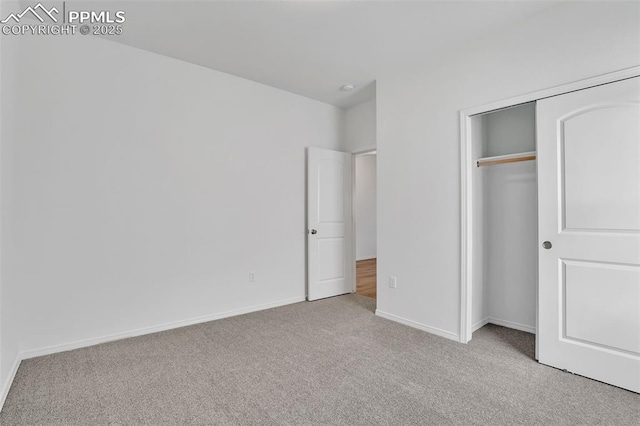 unfurnished bedroom with light colored carpet, baseboards, and a closet