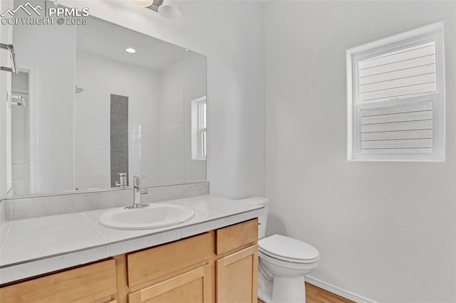 bathroom featuring toilet, vanity, a shower, and wood finished floors